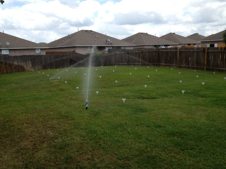 Sprinklers spraying a small grassy area.