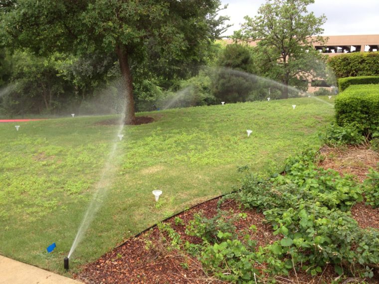 Sprinklers spraying a small grassy area.